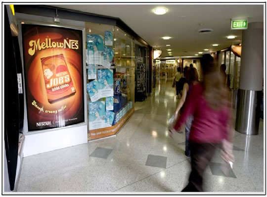 woman walking past backlit kiosk